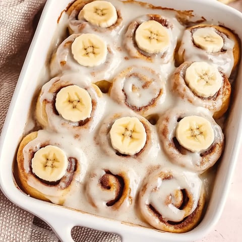 A white bowl filled with banana bread cinnamon rolls.