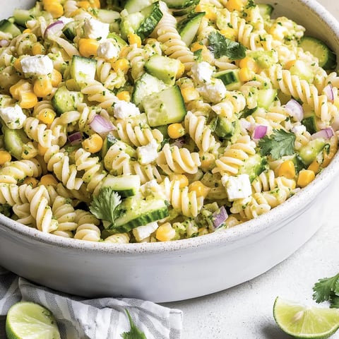 A bowl of pasta salad with cilantro and lime.