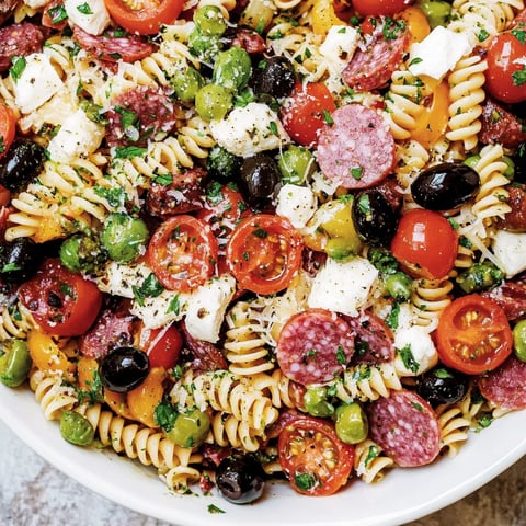 Ein großes, weißes Becher mit einer Mischung aus Pasta, Tomaten, Oliven, Zwiebeln und Käse.