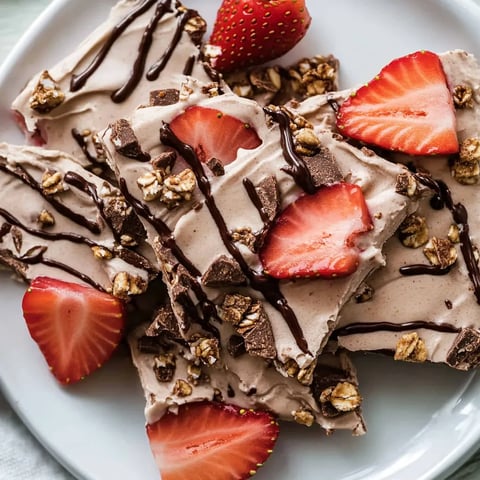 A plate of frozen yogurt bark with strawberries and nuts.