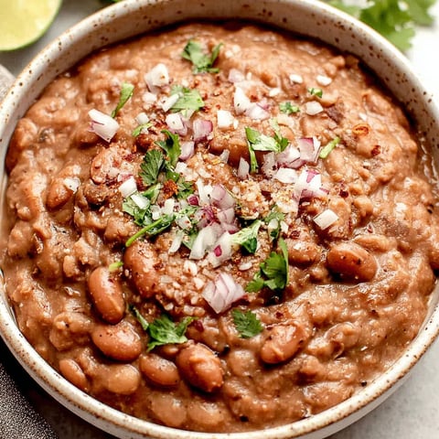 A bowl of refried beans with onions and spices.