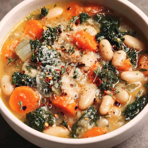 A bowl of soup with carrots and beans.