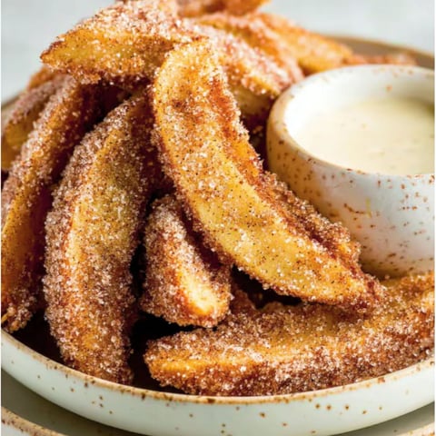 A plate of fried food with a bowl of vanilla icing.