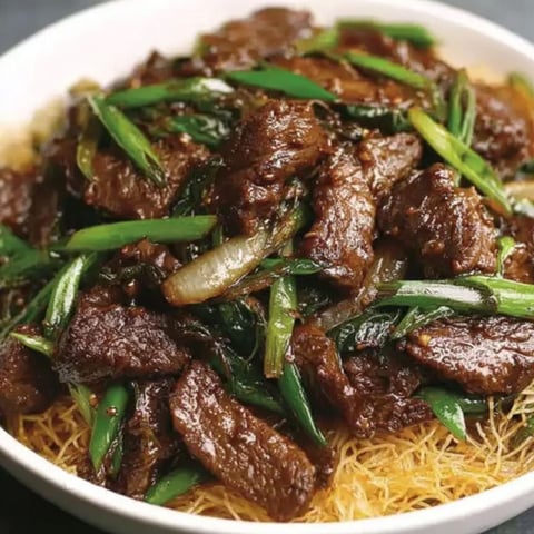A bowl of beef with noodles and vegetables.
