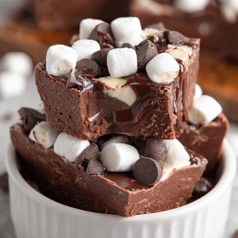 A stack of chocolate fudge cake with marshmallows on top.