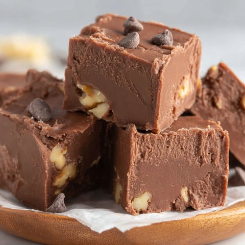 A plate of chocolate fudge with nuts on top.