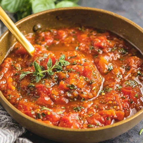A bowl of tomato sauce with a wooden spoon in it.