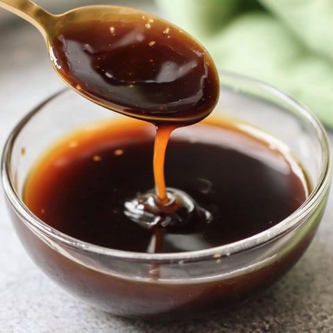 A spoon is in a bowl of sauce.