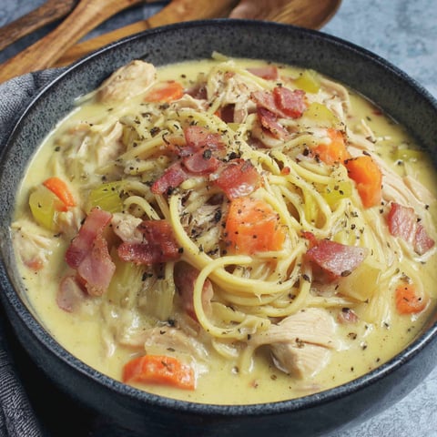 A bowl of soup with chicken, noodles, and vegetables.