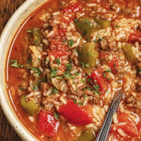 A bowl of soup with rice and peppers.