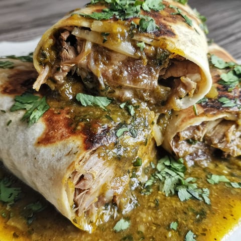 A chili verde hatch burrito is served on a plate.