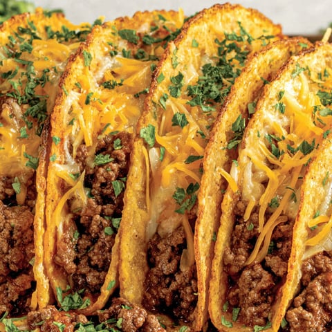 A plate of baked tacos with cheese and meat.
