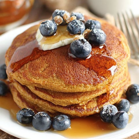 A stack of pancakes with blueberries on top.