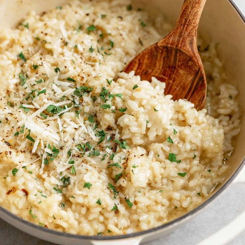 A bowl of rice with cheese and herbs.