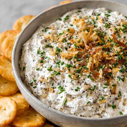 A bowl of French onion dip with a spoon in it.