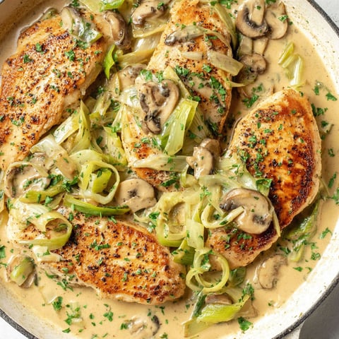 A pan of chicken with mushrooms and a creamy leek sauce.