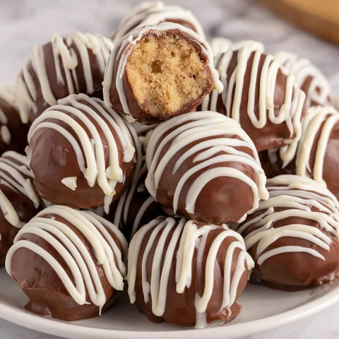 A plate of chocolate and white balls with a bite taken out of one.