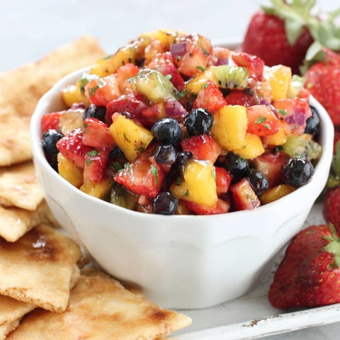 A bowl of fruit salsa with cinnamon chips.