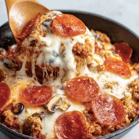 A bowl of crustless pizza with pepperoni and mushrooms.