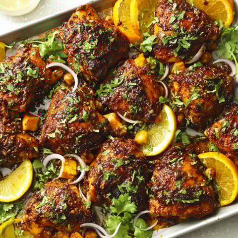 A pan of chicken with orange slices and herbs.