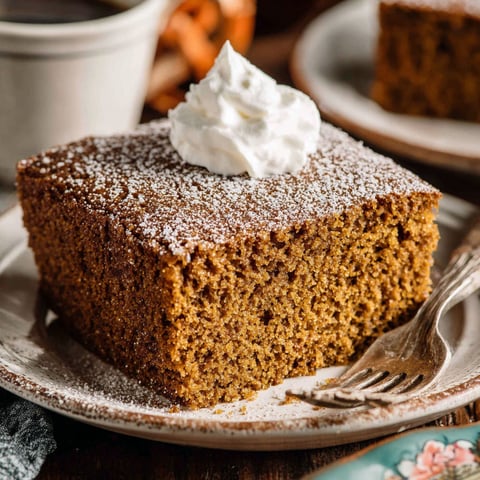 A slice of gingerbread cake with whipped cream on top.