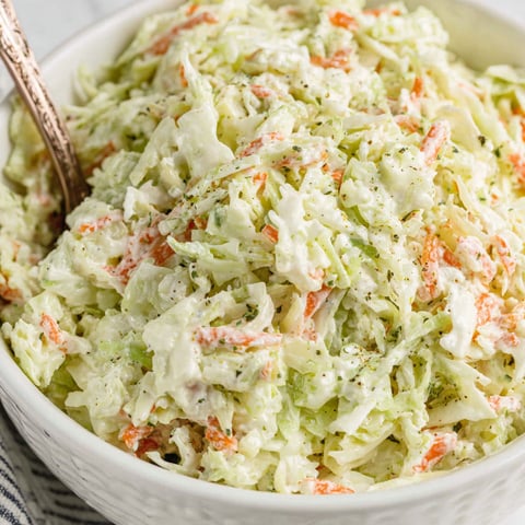 A bowl of coleslaw with a fork in it.