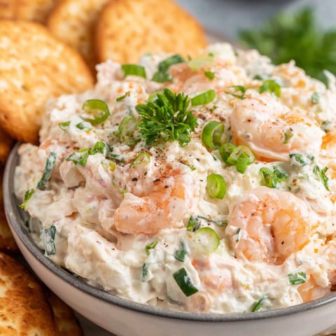 A bowl of shrimp dip with a green garnish.