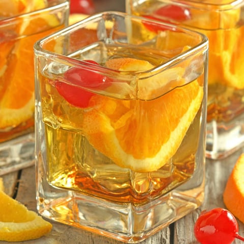Three glasses of orange juice with cherries on top.