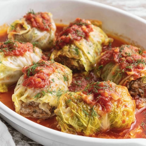 A white bowl filled with cabbage rolls.