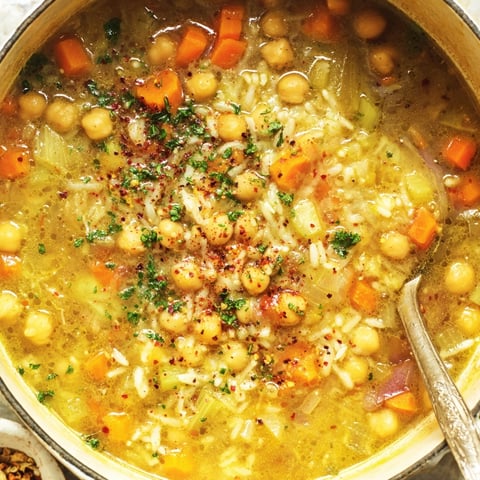 A bowl of soup with chickpeas and rice.